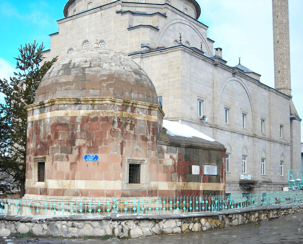 An octagonal Ottoman-era domed mausoleum (kümbet) dated 1587–88, standing in the courtyard of the 'Domed Mosque' in Çayıralan.